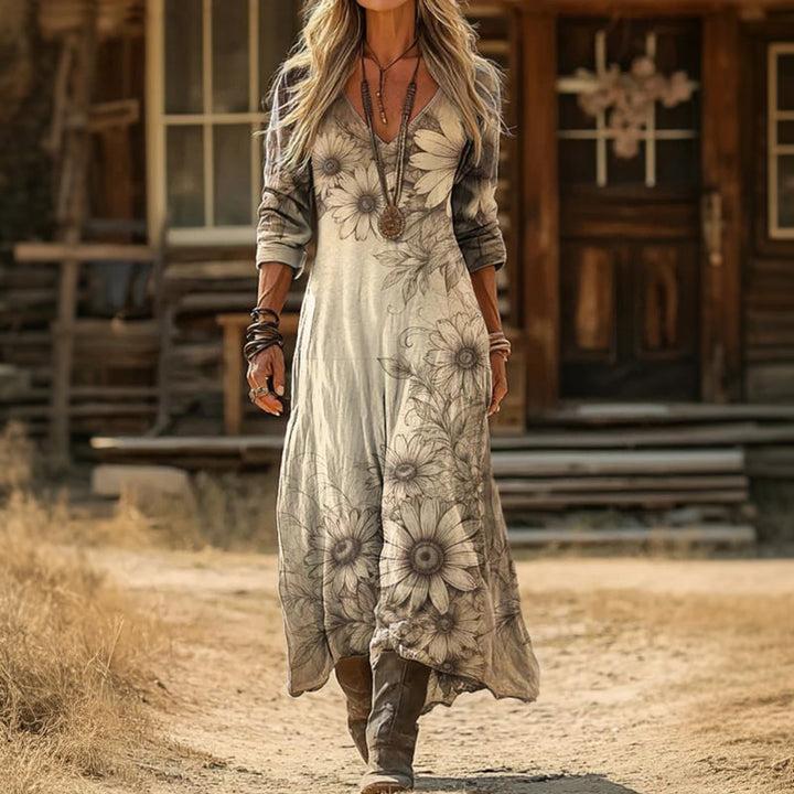 Lenora botanical sketch maxi dress worn with brown boots, showing the uneven hem